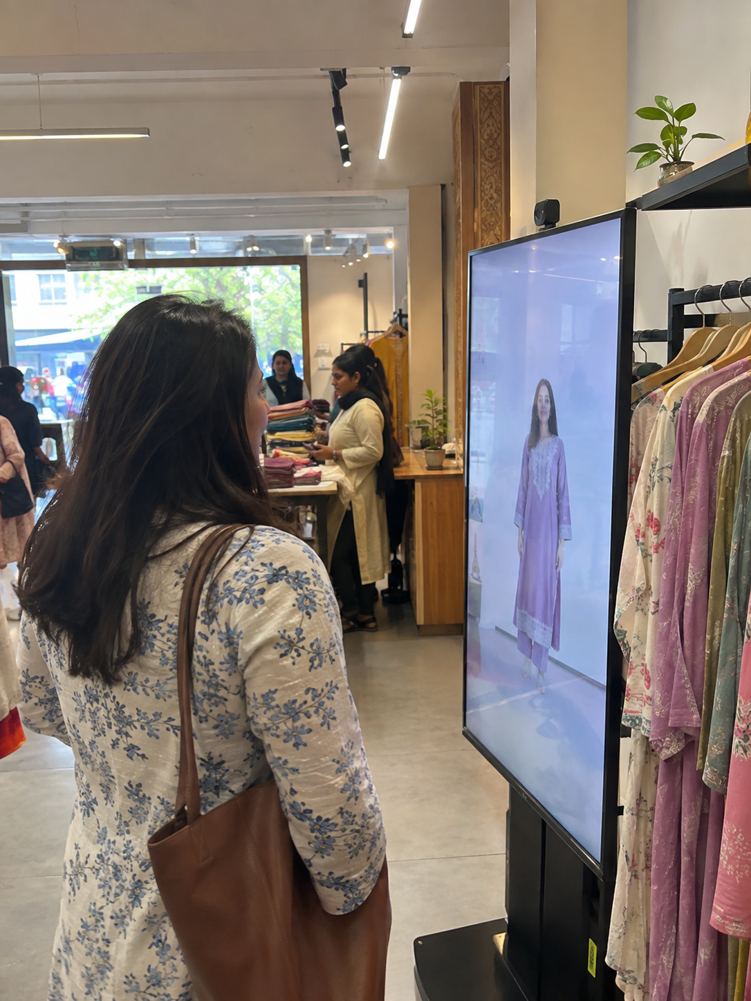 A shopper trying an outfit on the Any Screen TryOn mirror inside a boutique