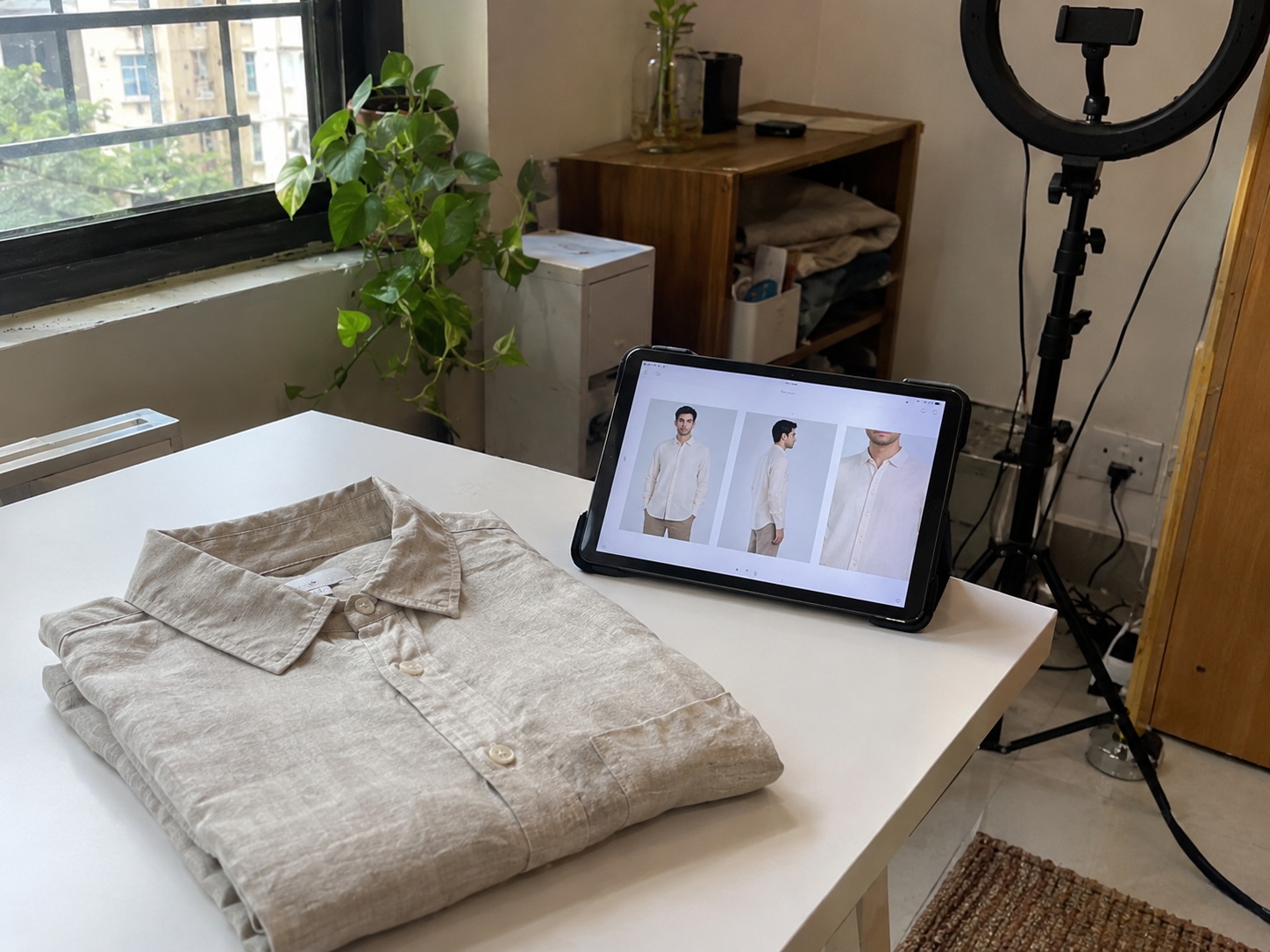 A folded shirt beside a tablet showing its finished AI photoshoot images